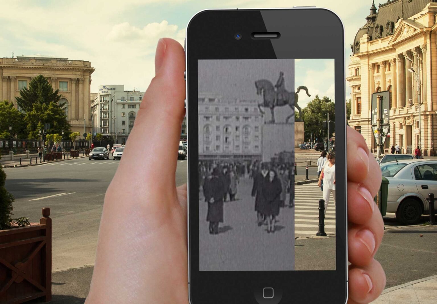 A phone held in the hand shows archive footage laid over Revolution Square in Bucharest.