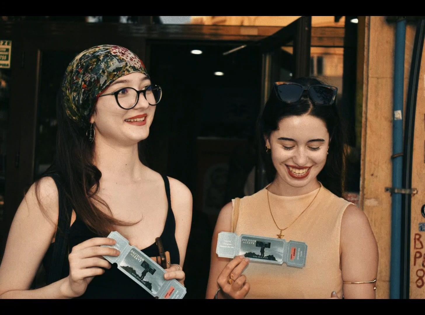 Două spectatoare cu biletele în mână, la intrarea în cinematograf