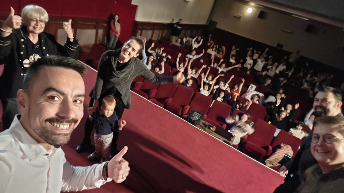 Sala plină de copii care ridică mâinile, la o proiecție