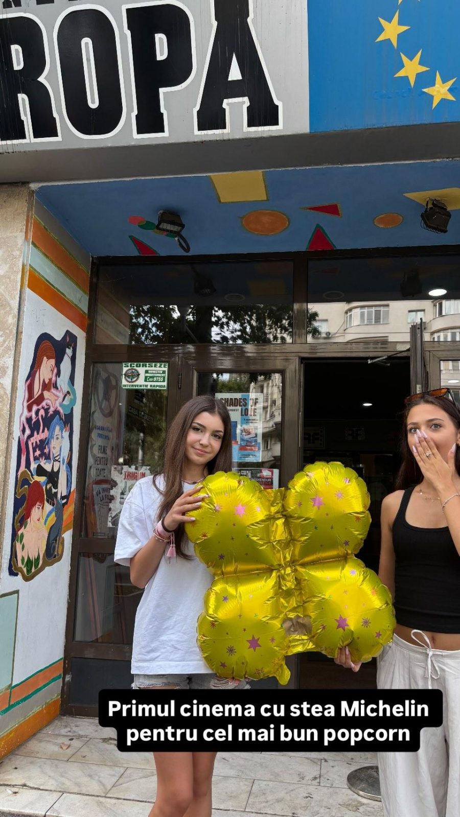 Două voluntare cu un balon în formă de floare, în fața intrării Cinema Europa.
