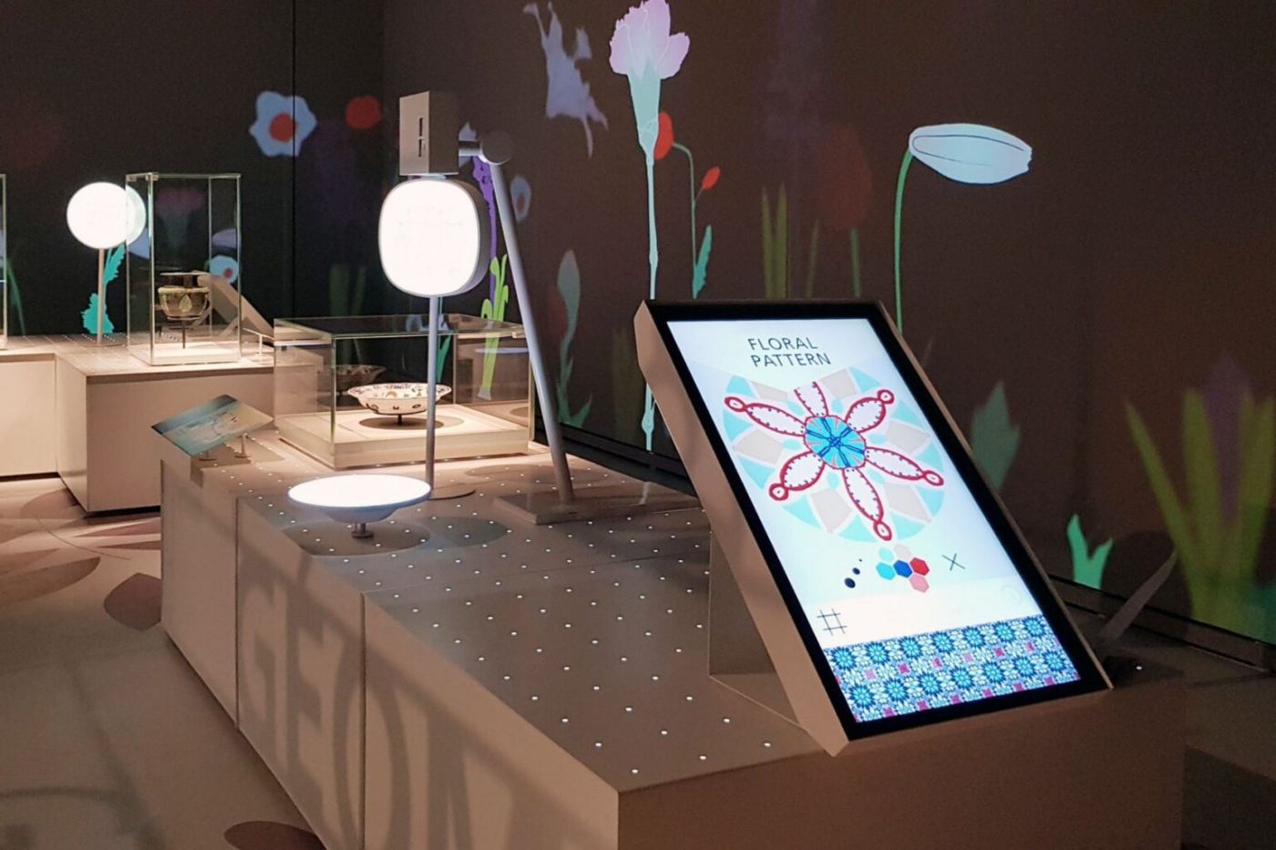 A screen showing a floral composition, beside the exhibition display cases