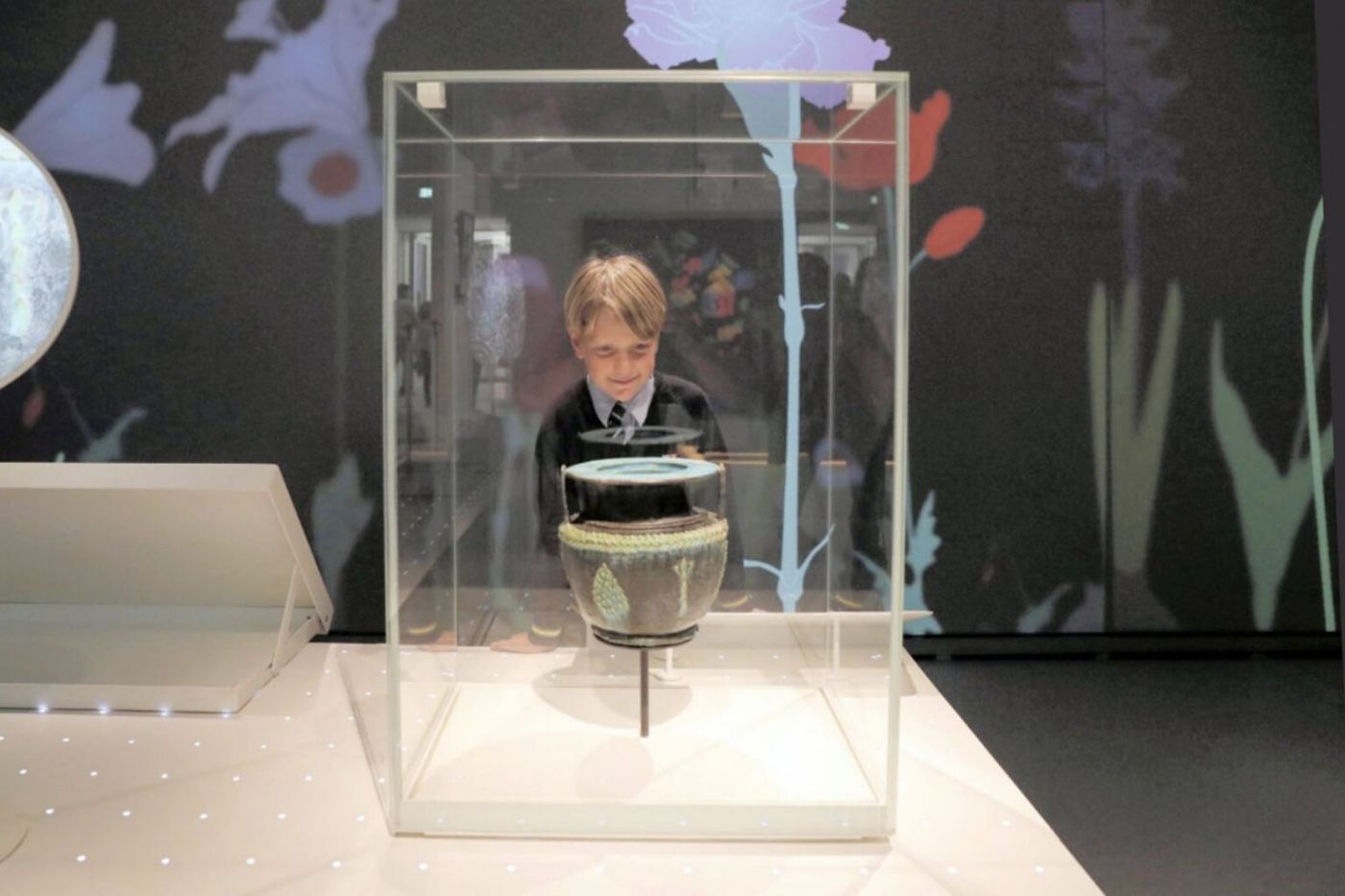 A child looking at a vase displayed in a case