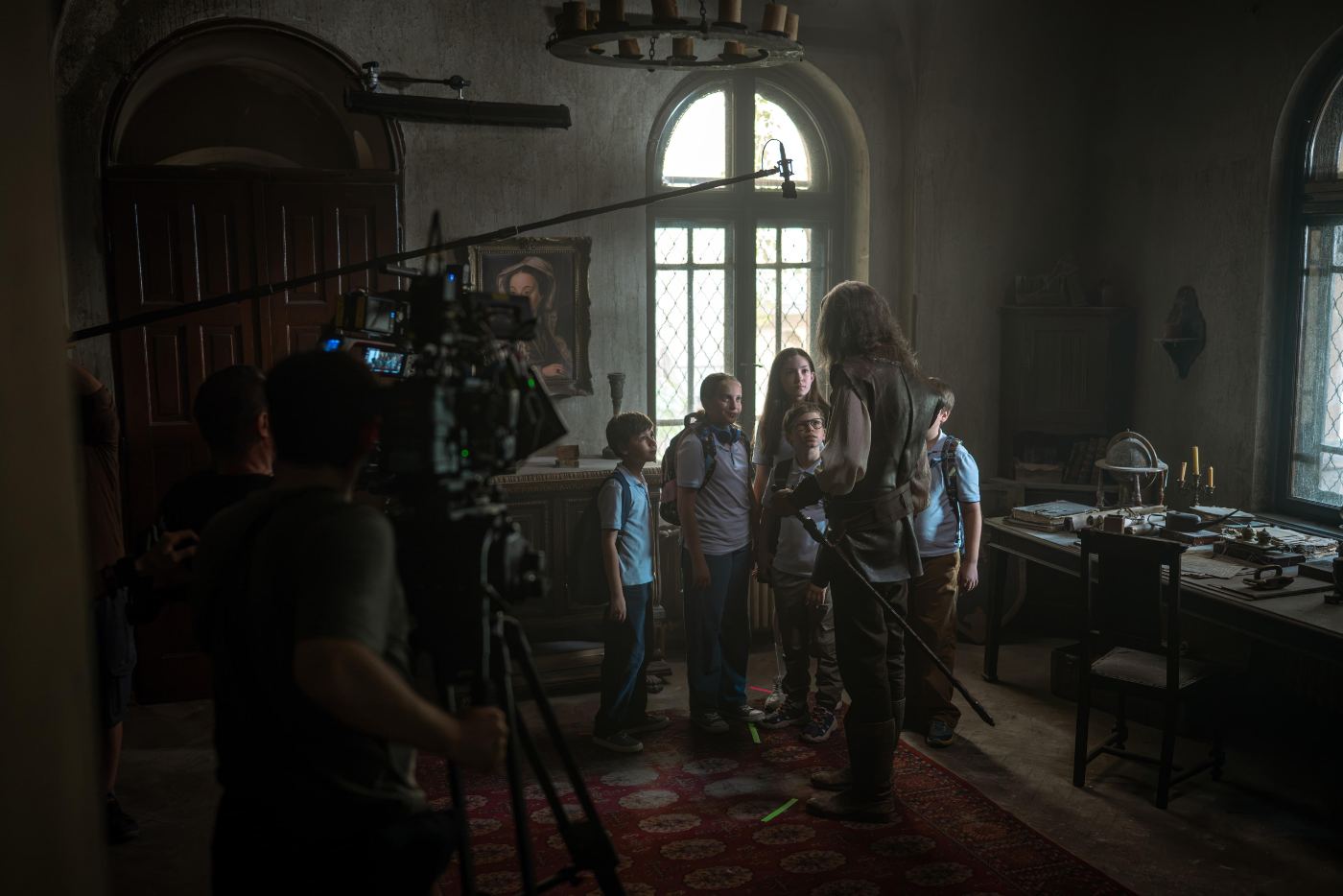 Echipa pe platoul de filmare, cu camera și microfonul îndreptate spre actori într-un decor de interior